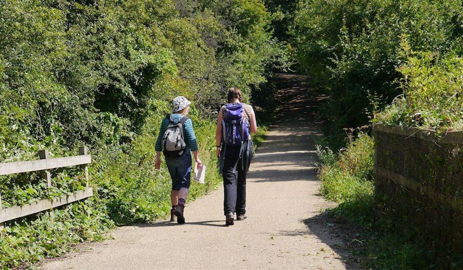 Two backpackers walking a country lane